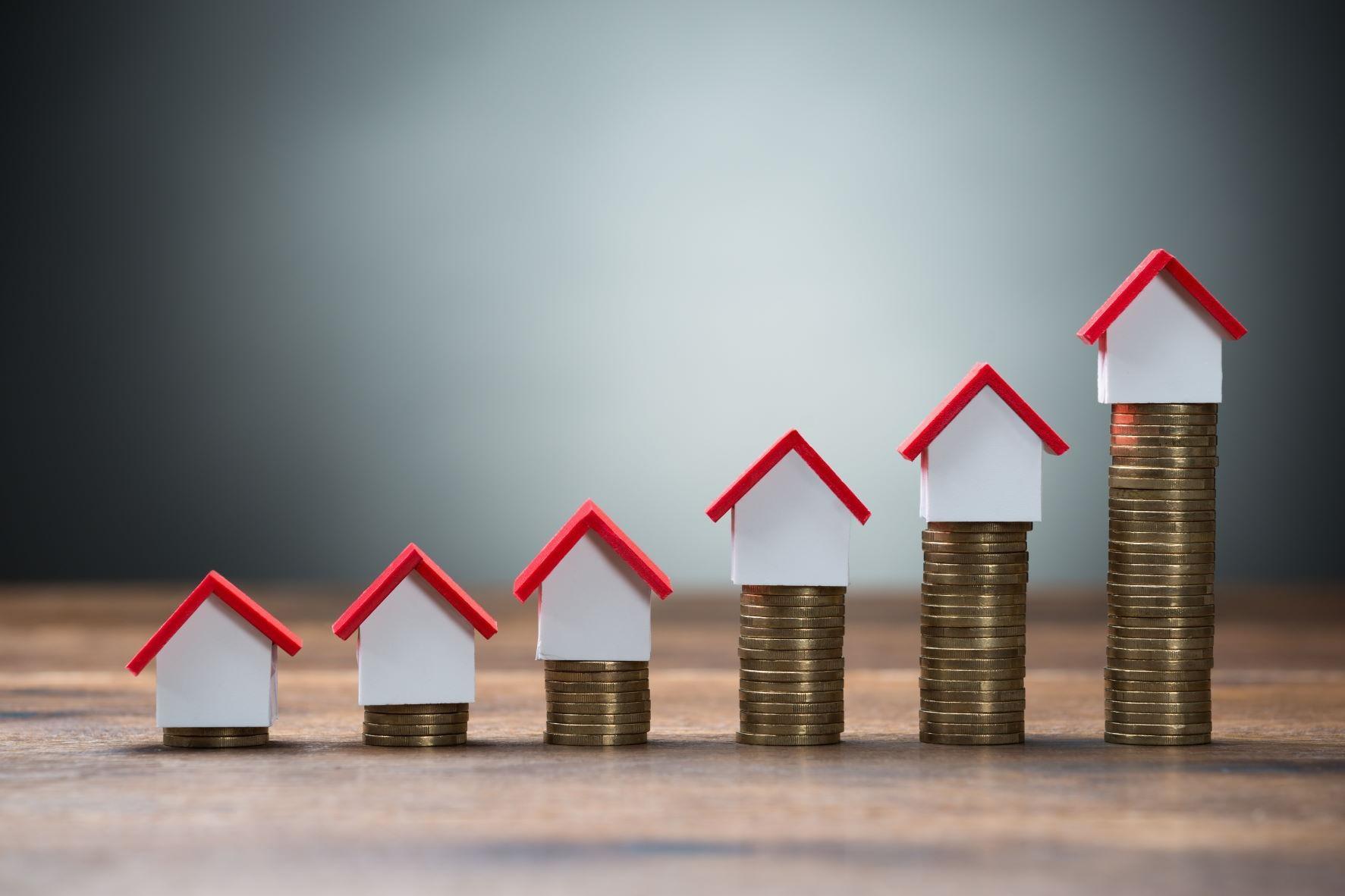 Houses sitting on increasing stacks of pennies showing costs rising