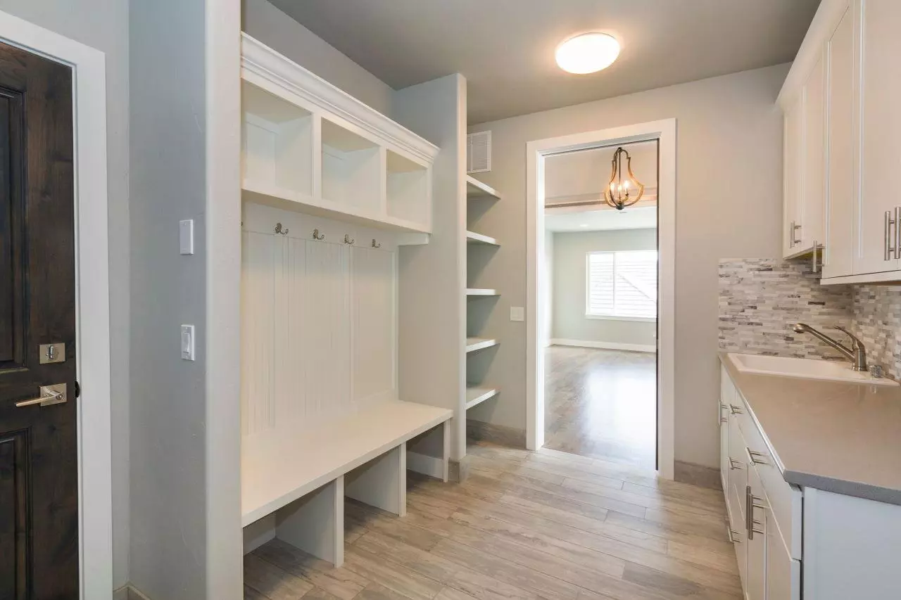 All white mud room with place to sit and take off shoes and hang jackets